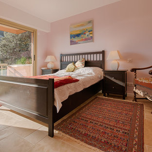 Foto de dormitorio principal, campestre, grande, con paredes rosas, suelo de piedra caliza, estufa de leña y marco de chimenea de metal