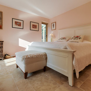 Diseño de dormitorio principal, romántico, grande, con paredes beige, suelo de piedra caliza, estufa de leña y marco de chimenea de metal
