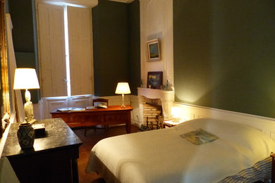 Diseño de habitación de invitados moderna de tamaño medio con paredes azules, suelo de madera en tonos medios, todas las chimeneas, marco de chimenea de piedra y suelo marrón