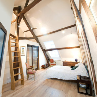 Inspiration pour une grand chambre mansardée ou avec mezzanine chalet avec un mur blanc et un sol en bois clair.