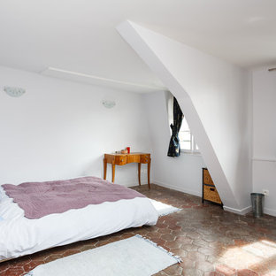 Diseño de dormitorio principal, de tamaño medio, con paredes blancas, suelo de baldosas de terracota, chimenea tradicional, marco de chimenea de yeso y suelo rojo