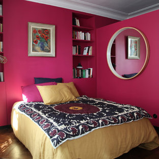 Cette image montre une chambre design avec un mur rose et un sol en bois foncé.
