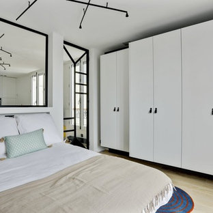 Exemple d'une chambre tendance avec un mur blanc, un sol en bois clair et un sol beige.