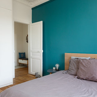 Ejemplo de dormitorio principal, escandinavo, de tamaño medio, con paredes azules, suelo de madera en tonos medios, chimenea tradicional, marco de chimenea de piedra y suelo marrón