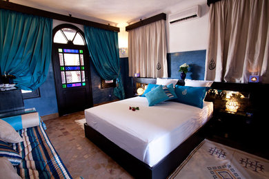Ejemplo de dormitorio principal mediterráneo grande sin chimenea con paredes azules y suelo de baldosas de terracota