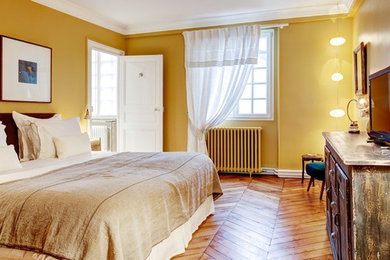 パリにある広いエクレクティックスタイルのおしゃれな主寝室 (黄色い壁、無垢フローリング、茶色い床)