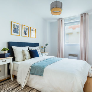 Cette image montre une chambre parentale nordique de taille moyenne avec un mur blanc, un sol en bois clair et un sol marron.
