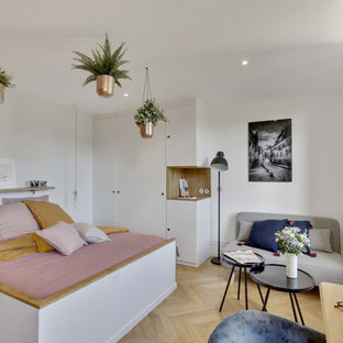 Cette photo montre une petit chambre parentale scandinave avec un mur blanc, un sol en bois clair et un sol beige.