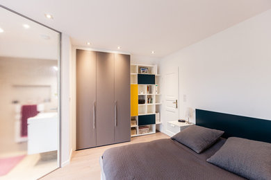 Exemple d'une chambre parentale tendance de taille moyenne avec un mur blanc, parquet clair et un sol beige.