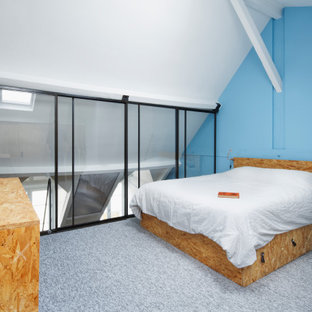 Diseño de dormitorio tipo loft, urbano, de tamaño medio, sin chimenea, con paredes azules, moqueta y suelo gris
