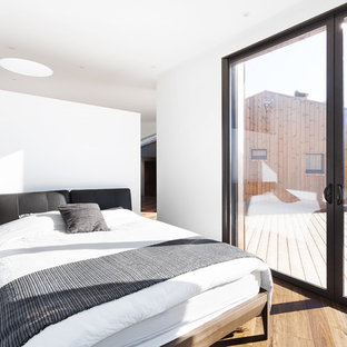 Réalisation d'une chambre parentale minimaliste de taille moyenne avec un mur blanc, un sol en bois brun et aucune cheminée.