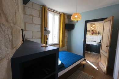 Aménagement d'une chambre parentale éclectique de taille moyenne avec un mur bleu, un sol en bois brun, aucune cheminée et un sol marron.