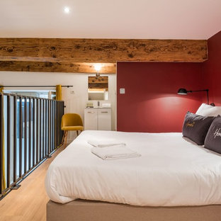 Idées déco pour une chambre mansardée ou avec mezzanine contemporaine avec un mur rouge, un sol en bois clair et un sol beige.