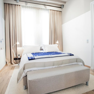 Exemple d'une grand chambre parentale tendance avec un mur blanc et un sol en bois clair.