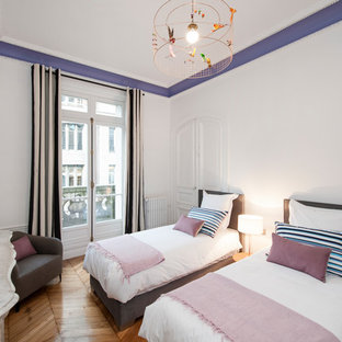 Inspiration pour une chambre d'amis design de taille moyenne avec un mur blanc, un sol en bois brun et une cheminée standard.