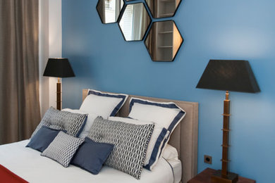 Idées déco pour une chambre parentale contemporaine de taille moyenne avec un mur bleu, un sol en bois brun et un sol beige.