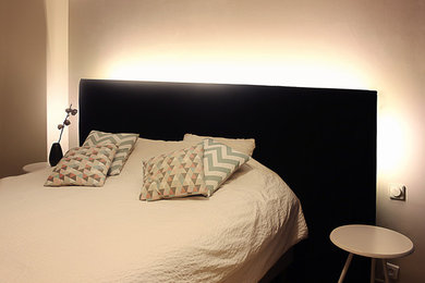 Imagen de dormitorio principal actual de tamaño medio con paredes beige y suelo de madera clara