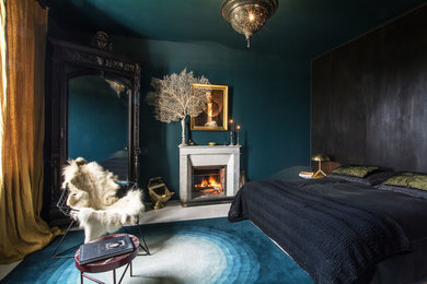 Cette image montre une chambre bohème avec un mur bleu, parquet peint, une cheminée standard, un manteau de cheminée en pierre et un sol blanc.