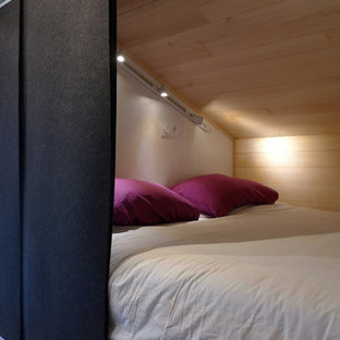 Modelo de dormitorio tipo loft, contemporáneo, pequeño, sin chimenea, con paredes negras y suelo de madera clara
