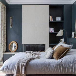 Réalisation d'une chambre design de taille moyenne avec un mur bleu, un sol en bois clair, une cheminée ribbon et un sol beige.