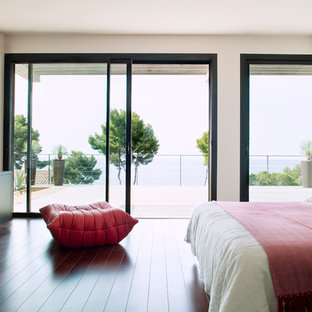 Idée de décoration pour une grand chambre parentale design avec un mur blanc et un sol en bois foncé.