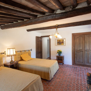 Inspiration pour une chambre méditerranéenne avec un mur blanc, un sol en carreau de terre cuite et un sol rouge.