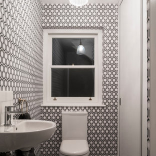 This is an example of a contemporary cloakroom in Other with a one-piece toilet, black walls, a wall-mounted sink, grey floors and white worktops.