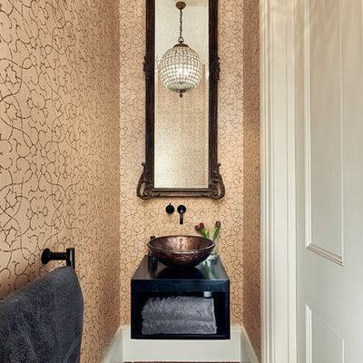 Powder room - small traditional brown floor powder room idea in London with open cabinets, black cabinets, beige walls, a vessel sink and black countertops