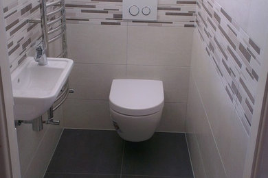 Inspiration for a small modern cloakroom in West Midlands with a wall mounted toilet, multi-coloured tiles, ceramic tiles, a wall-mounted sink and white walls.
