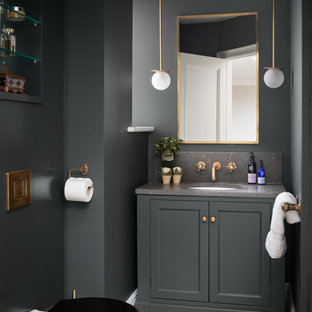 Photo of a medium sized traditional cloakroom in London with a one-piece toilet, light hardwood flooring, limestone worktops, grey worktops, recessed-panel cabinets, grey cabinets, grey walls, a submerged sink and beige floors.