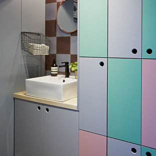 This is an example of a bohemian cloakroom in London with flat-panel cabinets and purple walls.