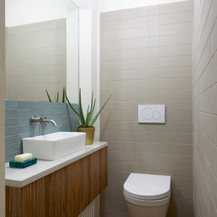Ispirazione per un bagno di servizio contemporaneo con ante lisce, ante in legno scuro, WC sospeso, piastrelle grigie, pareti bianche, lavabo a bacinella, pavimento rosso, top bianco e mobile bagno sospeso