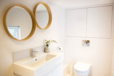 Inspiration for a mid-sized modern gray tile and ceramic tile gray floor powder room remodel in Surrey with flat-panel cabinets, gray cabinets, a one-piece toilet, gray walls and a wall-mount sink