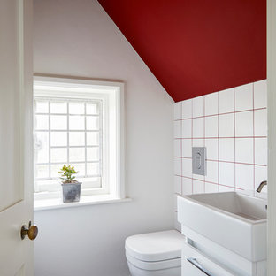Photo of a contemporary cloakroom in Surrey with flat-panel cabinets, white cabinets, white tiles, white walls, a console sink and black floors.