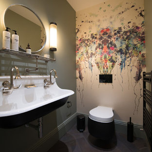Small classic cloakroom in London with a wall mounted toilet, green walls, dark hardwood flooring, a wall-mounted sink and brown floors.