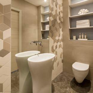 Aménagement d'un WC et toilettes contemporain de taille moyenne avec un lavabo intégré, un WC suspendu, un mur beige, un sol en carrelage de céramique, un carrelage beige et des portes de placard en bois clair.