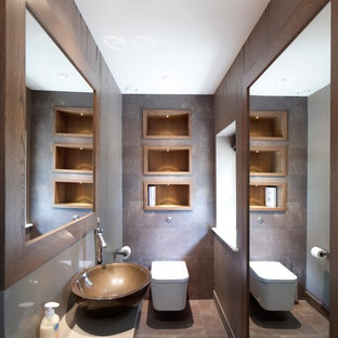 Idee per un bagno di servizio minimal con lavabo a bacinella, WC sospeso e piastrelle marroni