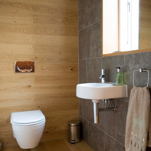 Esempio di un piccolo bagno di servizio design con lavabo sospeso, WC sospeso, piastrelle in gres porcellanato, parquet chiaro e piastrelle grigie