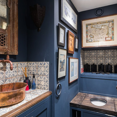 Powder room - small mediterranean multicolored tile powder room idea in London with blue cabinets, blue walls, a vessel sink, tile countertops, a one-piece toilet and multicolored countertops