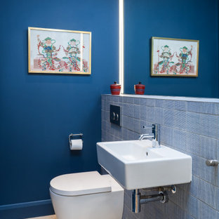 Immagine di un piccolo bagno di servizio minimalista con WC sospeso, piastrelle blu, piastrelle in ceramica, pareti blu, pavimento in pietra calcarea, lavabo sospeso, top piastrellato, pavimento beige e top blu