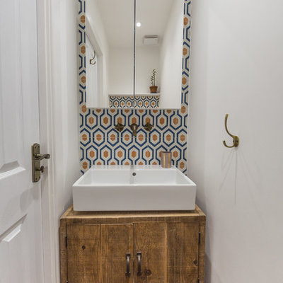Inspiration for a mediterranean blue tile, orange tile and white tile powder room remodel in London with flat-panel cabinets, medium tone wood cabinets, white walls and a vessel sink