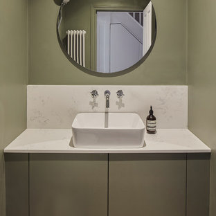 Inspiration for a scandinavian cloakroom in London with flat-panel cabinets, green cabinets, green walls, medium hardwood flooring, a vessel sink and white worktops.