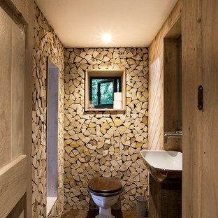 Idée de décoration pour un WC et toilettes chalet de taille moyenne avec un WC à poser, une vasque, un sol marron et des portes de placard en bois sombre.