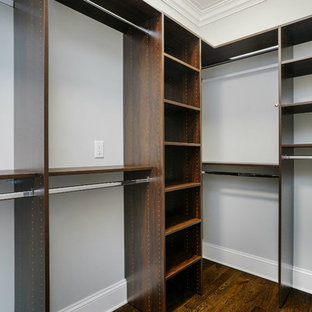 Modelo de armario vestidor unisex, tradicional, de tamaño medio, con armarios abiertos, puertas de armario de madera en tonos medios, suelo de madera oscura y suelo marrón