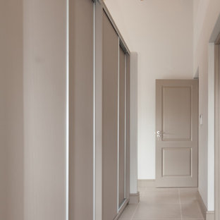 Ejemplo de armario vestidor unisex, de estilo de casa de campo, de tamaño medio, con armarios con paneles lisos, puertas de armario beige y suelo de baldosas de porcelana