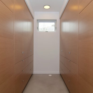 Foto de armario vestidor unisex, escandinavo, grande, con armarios con paneles lisos, puertas de armario de madera clara y suelo de cemento