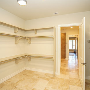 Ispirazione per una cabina armadio unisex country di medie dimensioni con ante con bugna sagomata, ante beige, pavimento in travertino e pavimento beige
