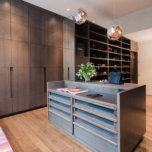 Large trendy gender-neutral brown floor and medium tone wood floor dressing room photo in New York with flat-panel cabinets and dark wood cabinets