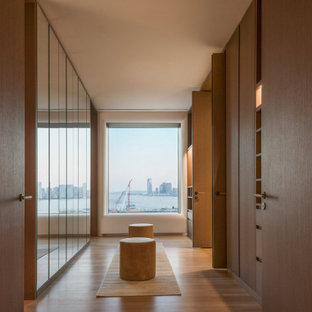 Inspiration for a modern light wood floor and beige floor walk-in closet remodel in New York with flat-panel cabinets and light wood cabinets
