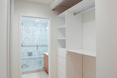 Ejemplo de armario unisex actual de tamaño medio con armarios abiertos, puertas de armario blancas y suelo de madera clara